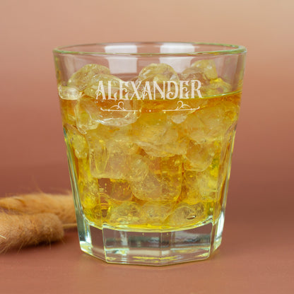 Personalisiertes Leonardo-Glas mit Namensgravur und Ornamentverzierung, goldfarbenes Getränk auf braunem Hintergrund