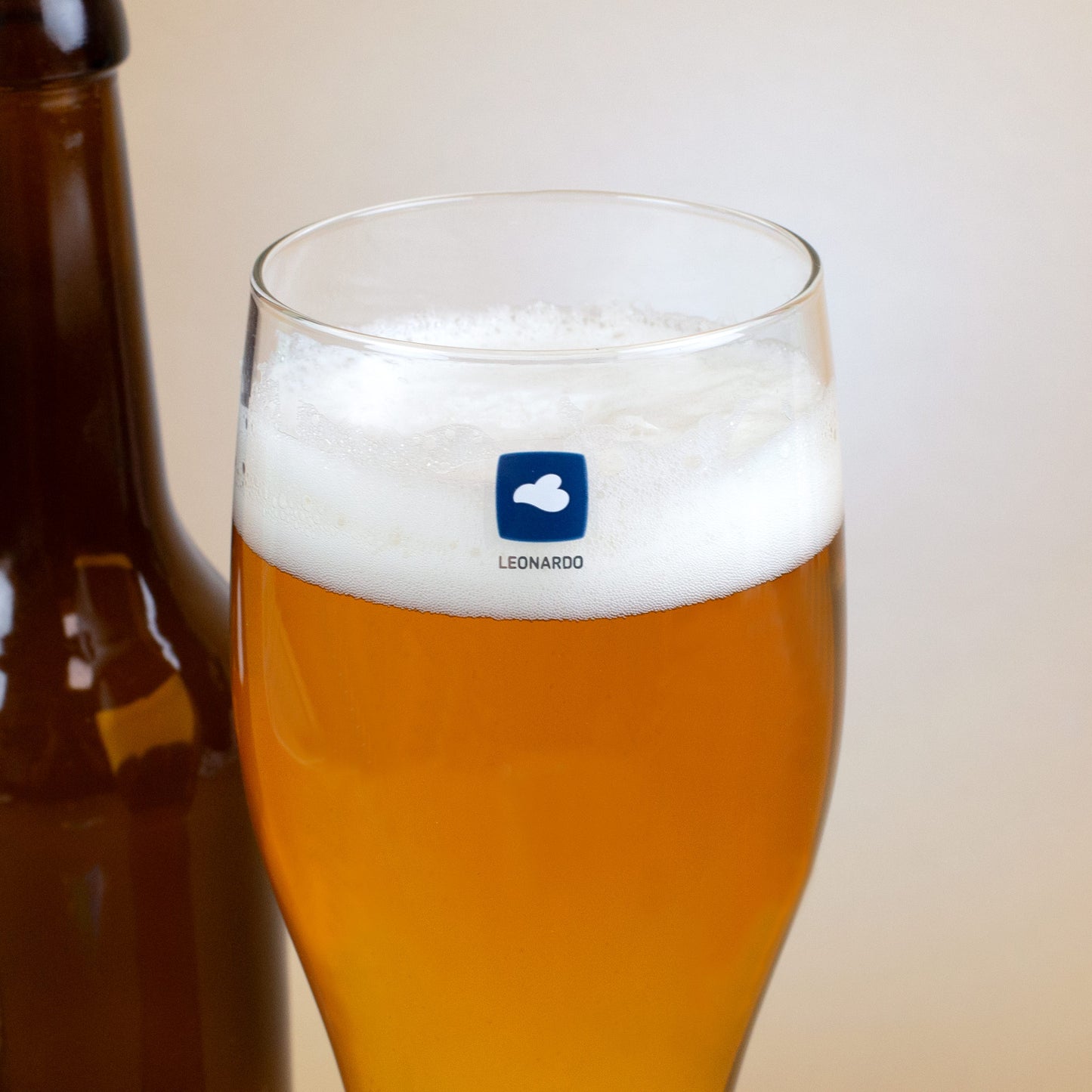 Detailaufnahme: Leonardo-Weizenglas mit Logo auf der Rückseite, gefüllt mit Bier.