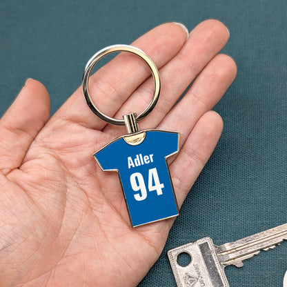Blauer Trikot-Schlüsselanhänger mit „Adler 94“ in Hand gehalten