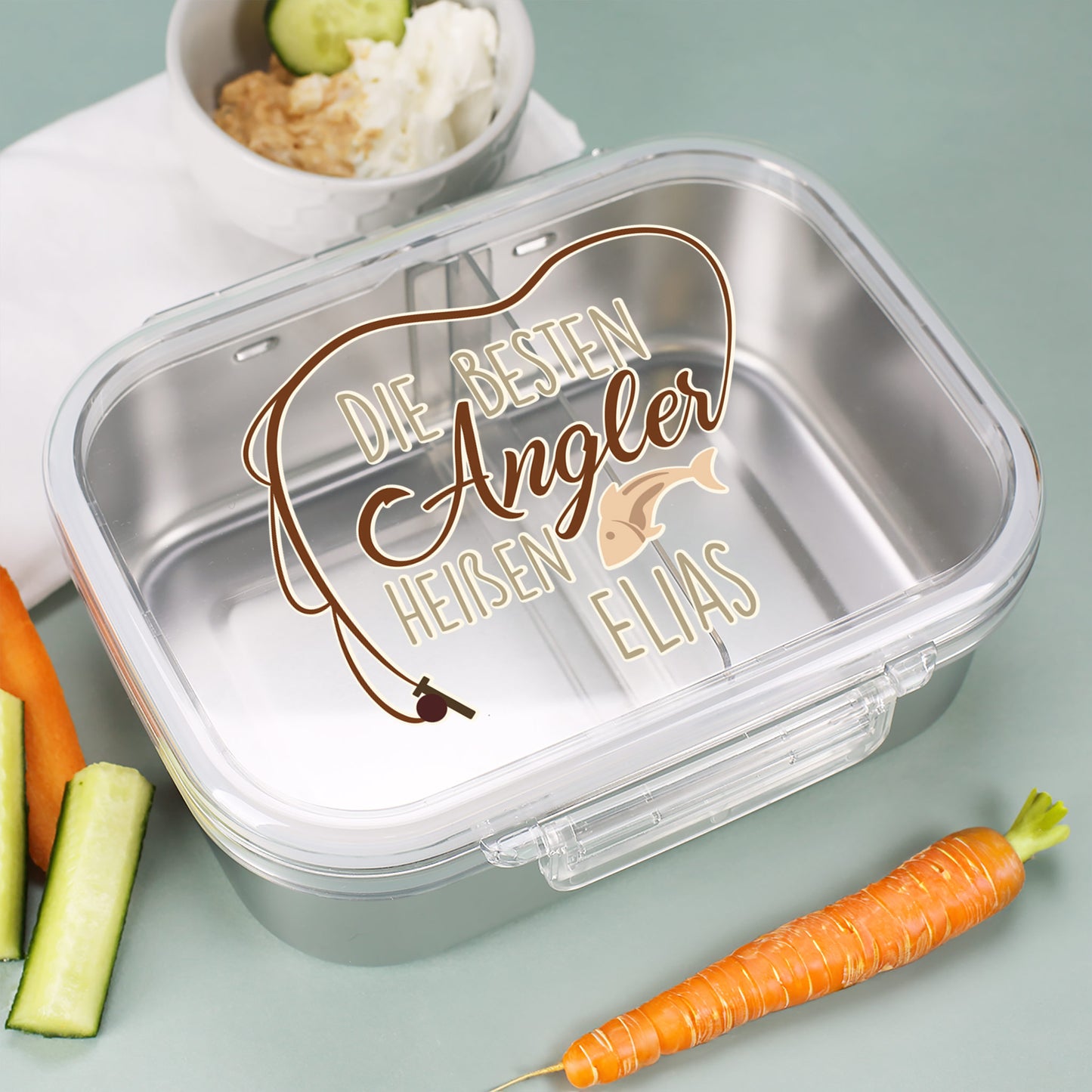Personalisierte Brotdose „Die besten Angler heißen Elias“ mit Gemüse im Hintergrund