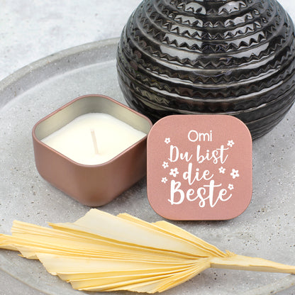 Roségoldene Duftkerze mit Vanilleduft neben schwarzer Vase, Deckel mit Aufschrift „Omi Du bist die Beste“