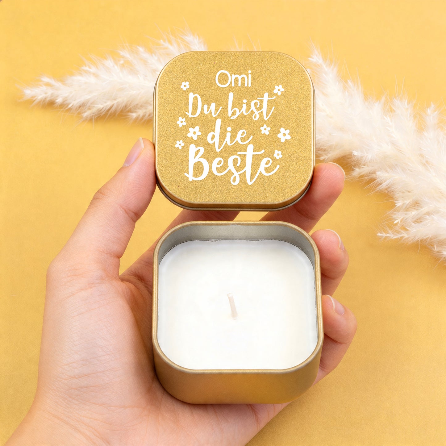 Goldene Duftkerze mit Vanilleduft in der Hand, personalisierter Deckel mit Aufschrift „Omi Du bist die Beste“