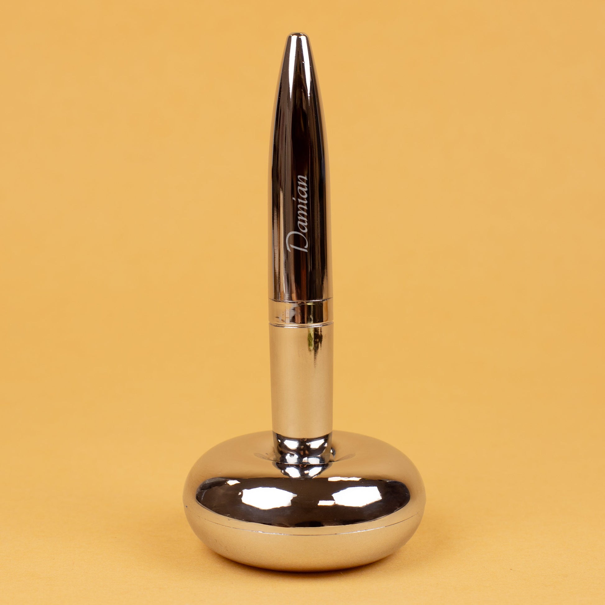 Magischer Kugelschreiber mit Namensgravur stehend in Ständer auf gelbem Hintergrund