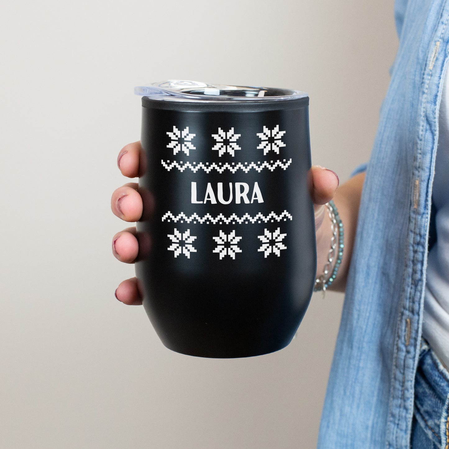 Schwarze Thermotasse mit Strickmuster und Namensaufdruck Laura in Händen gehalten
