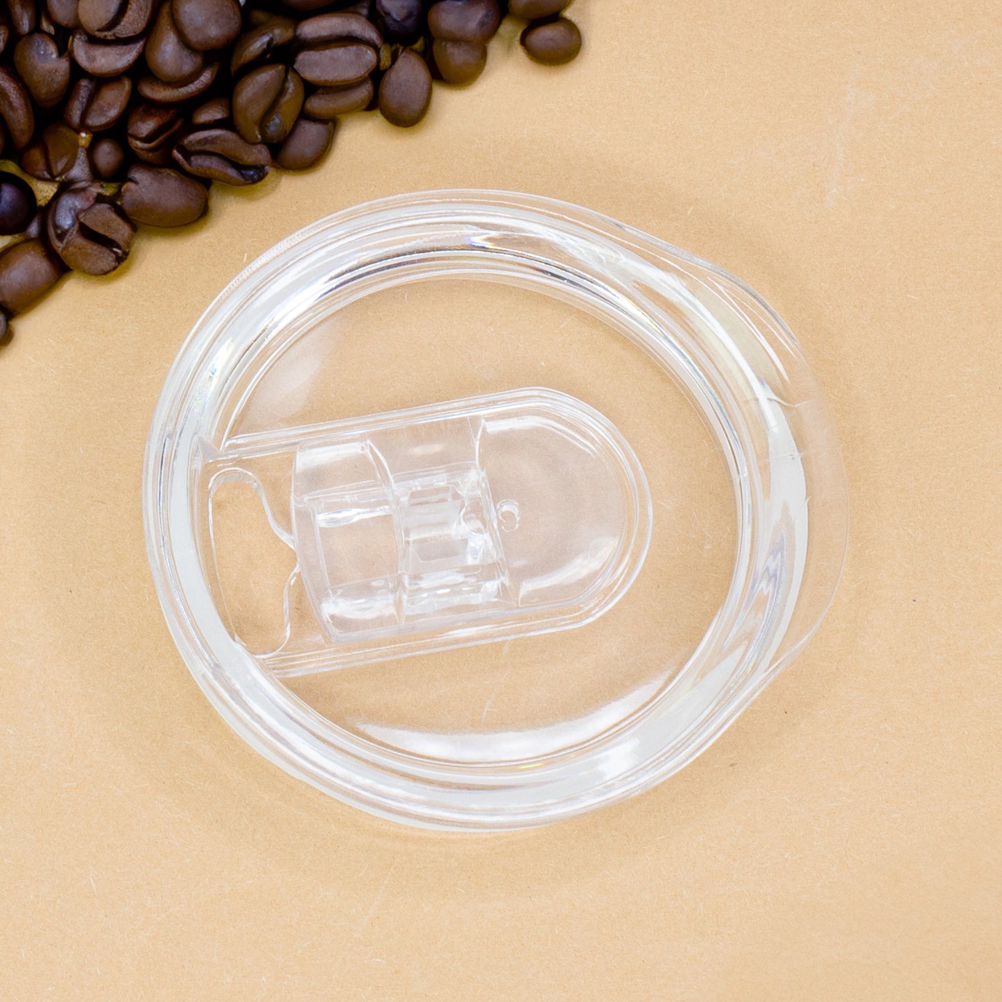 Transparenter Deckel des Thermobechers einzeln auf heller Unterlage mit Kaffeebohnen daneben