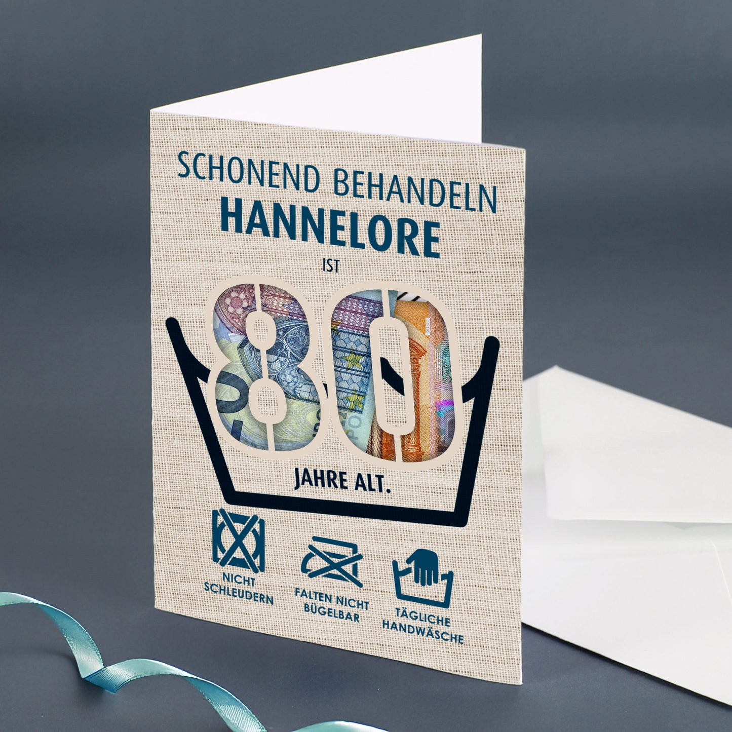 Geöffnete Klappkarte mit Name „Hannelore“ zum 80. Geburtstag, sichtbare Geldscheine hinter den Zahlen, nebenliegender weißer Umschlag