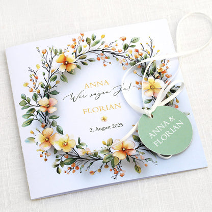 Einladungskarte zur Hochzeit mit Blütenkranz und rundem Anhänger