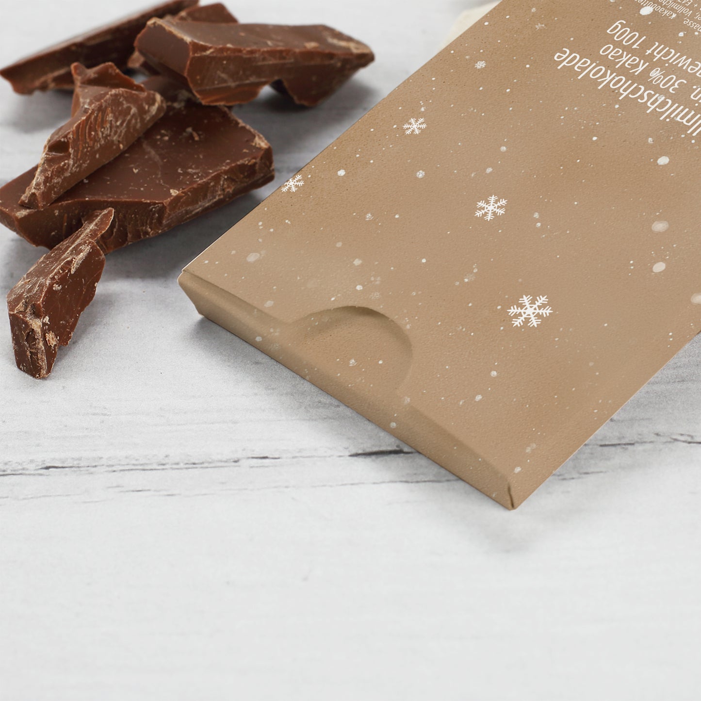 Personalisierte Schokolade mit Foto im Herz und Weihnachtsmann-Design. Die Verpackung trägt den Namen „Leonie“ über dem Spruch „Du bist nicht nur an Weihnachten besonders“. Das Produkt ist umgeben von Tannenzweigen und Sternanis auf einem hellen, winterlich dekorierten Untergrund.