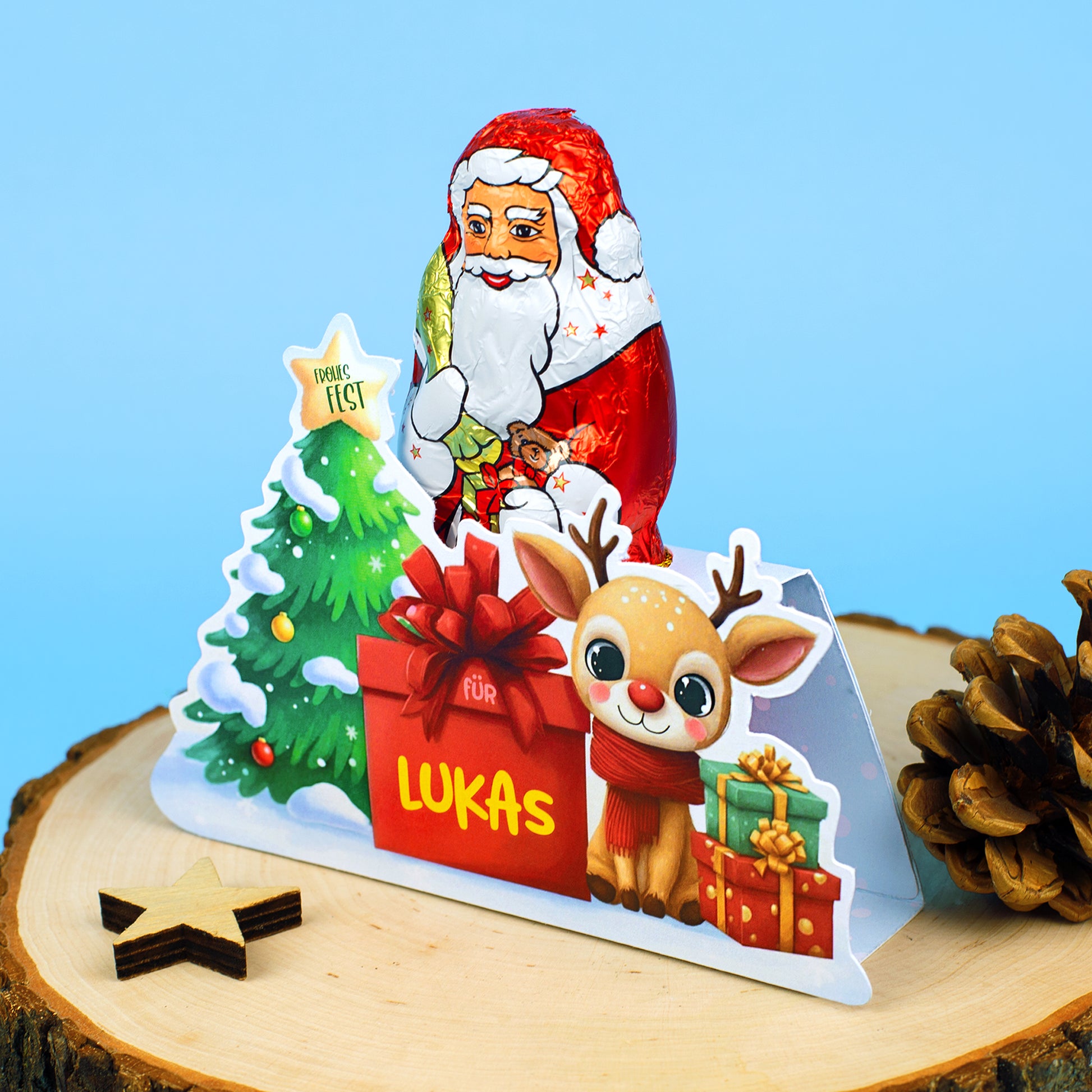 Dekorativ aufgestellte personalisierte Verpackung mit Rentiermotiv und Lindt Weihnachtsmann vor blauem Hintergrund