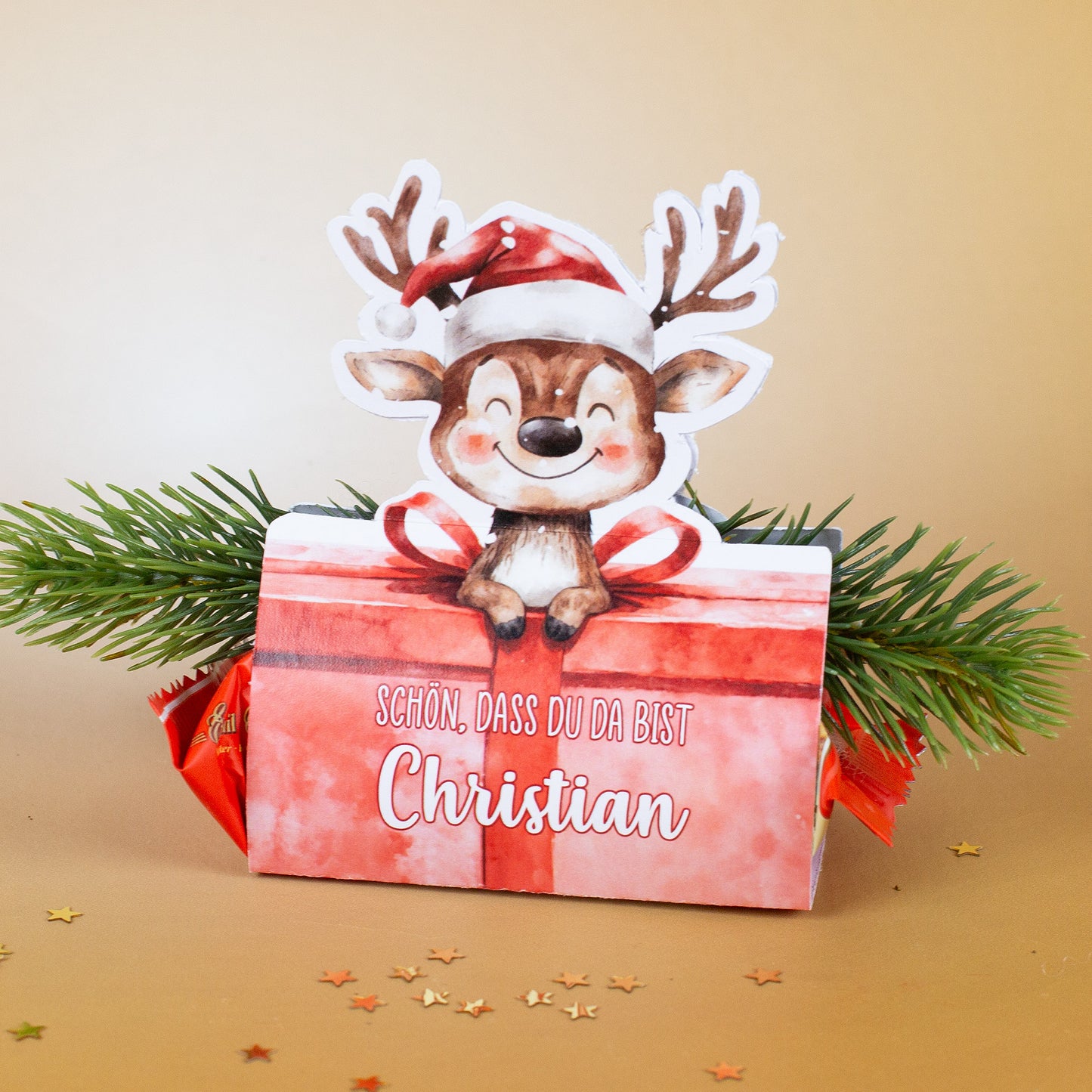 Produktfoto des Rentier-Mini-Stollens mit Namensaufdruck Christian und goldenem Hintergrund, dekoriert mit Tannenzweig.