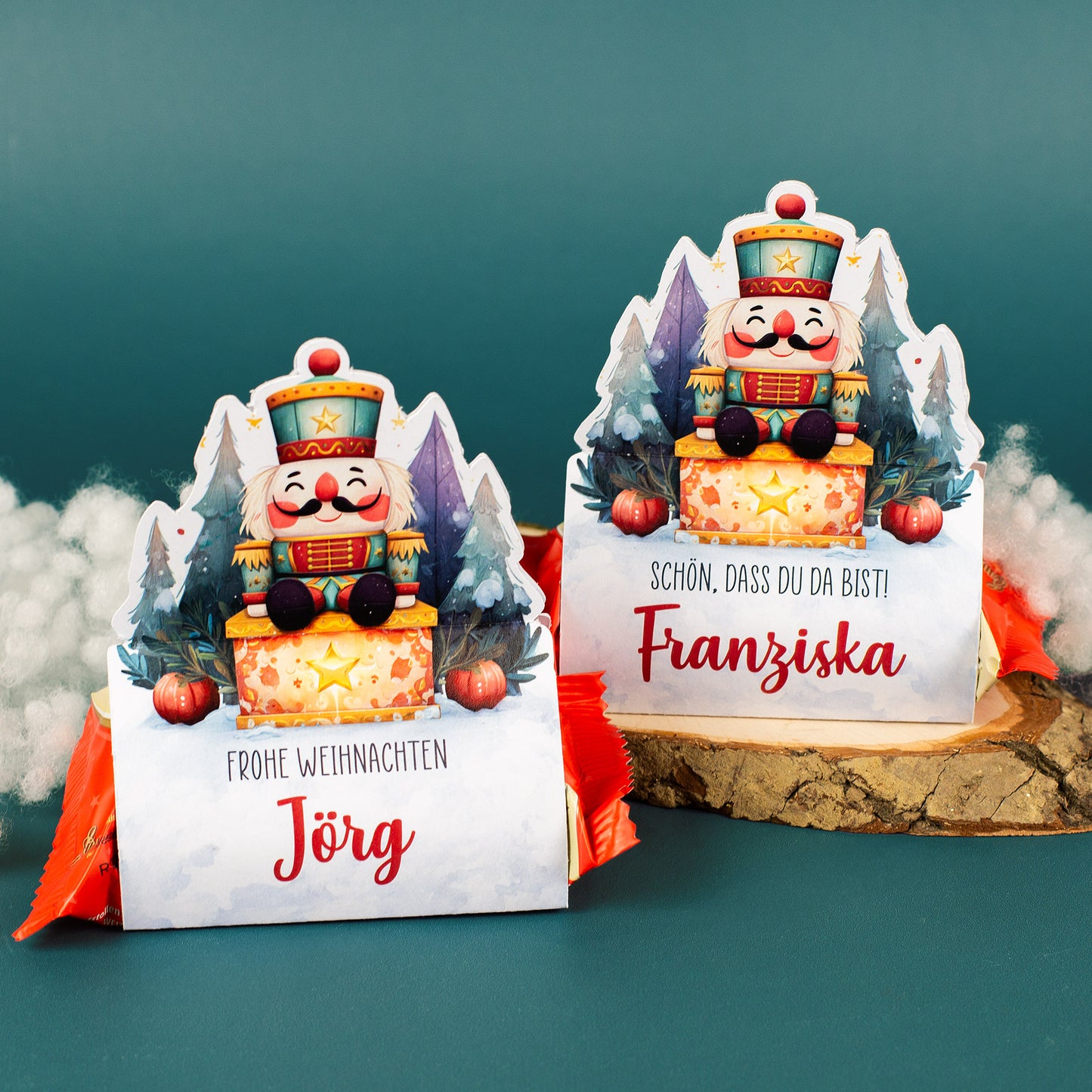 Personalisierte Nussknacker-Stollenverpackungen für Jörg und Franziska, dekorativ arrangiert mit Schnee und Holzunterlage