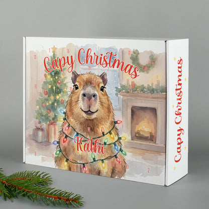 Adventskalender mit Name Kathi personalisiert und Capybara Motiv vor Weihnachtsbaum und Kamin