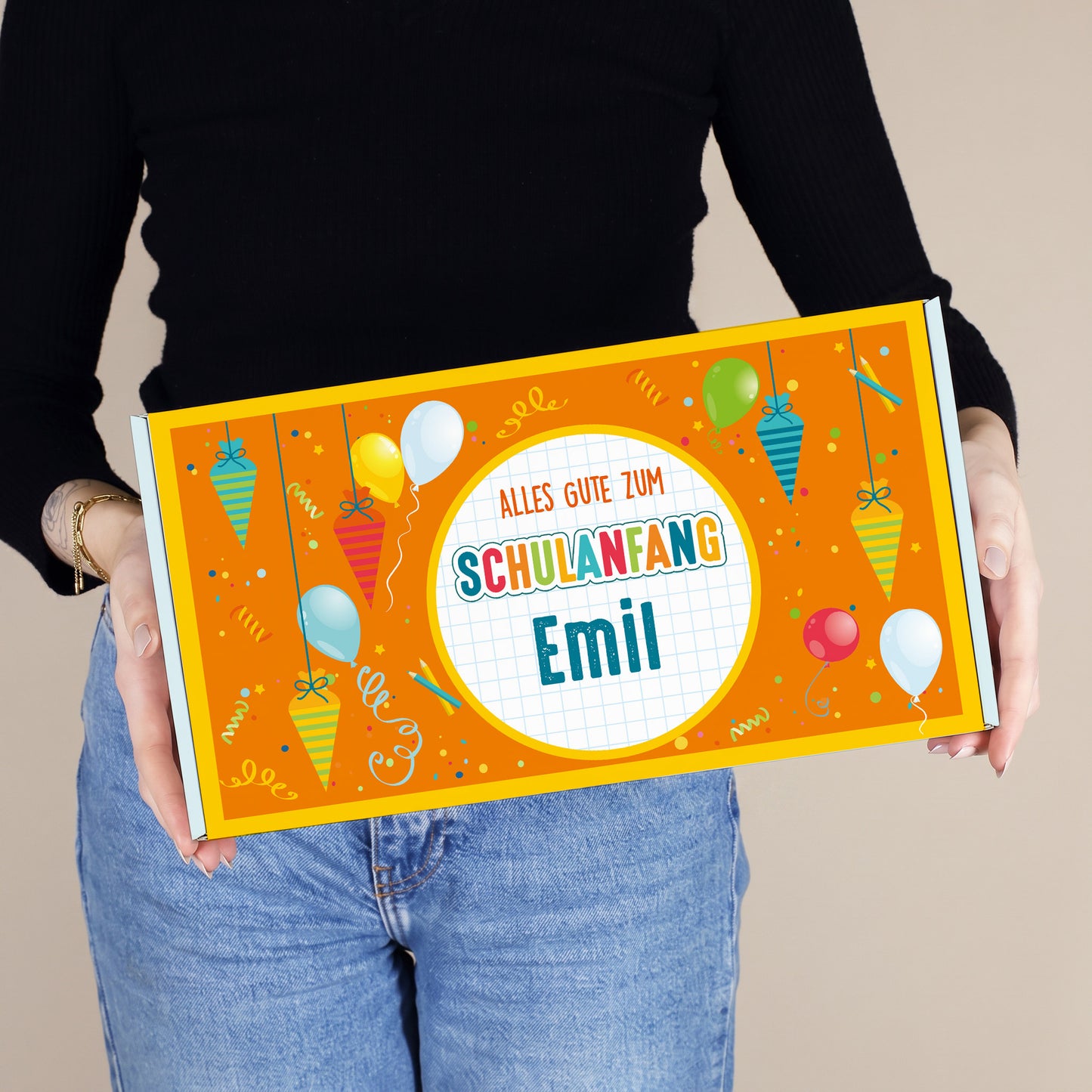 Mittlere personalisierte Geschenkbox mit Wunschname und buntem Schultüten-Motiv, von einer Person präsentiert