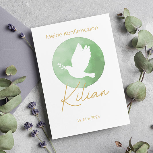 Einladungskarte zur Konfirmation mit einem stilvollen, grünen Aquarell-Hintergrund und einer weißen Taube mit Olivenzweig im Schnabel. Der Name "Kilian" ist in eleganter goldener Schrift gestaltet, das Datum der Konfirmation darunter platziert. Die Karte liegt auf einer natürlichen Unterlage mit Eukalyptus und Lavendel, was eine harmonische und festliche Atmosphäre schafft.