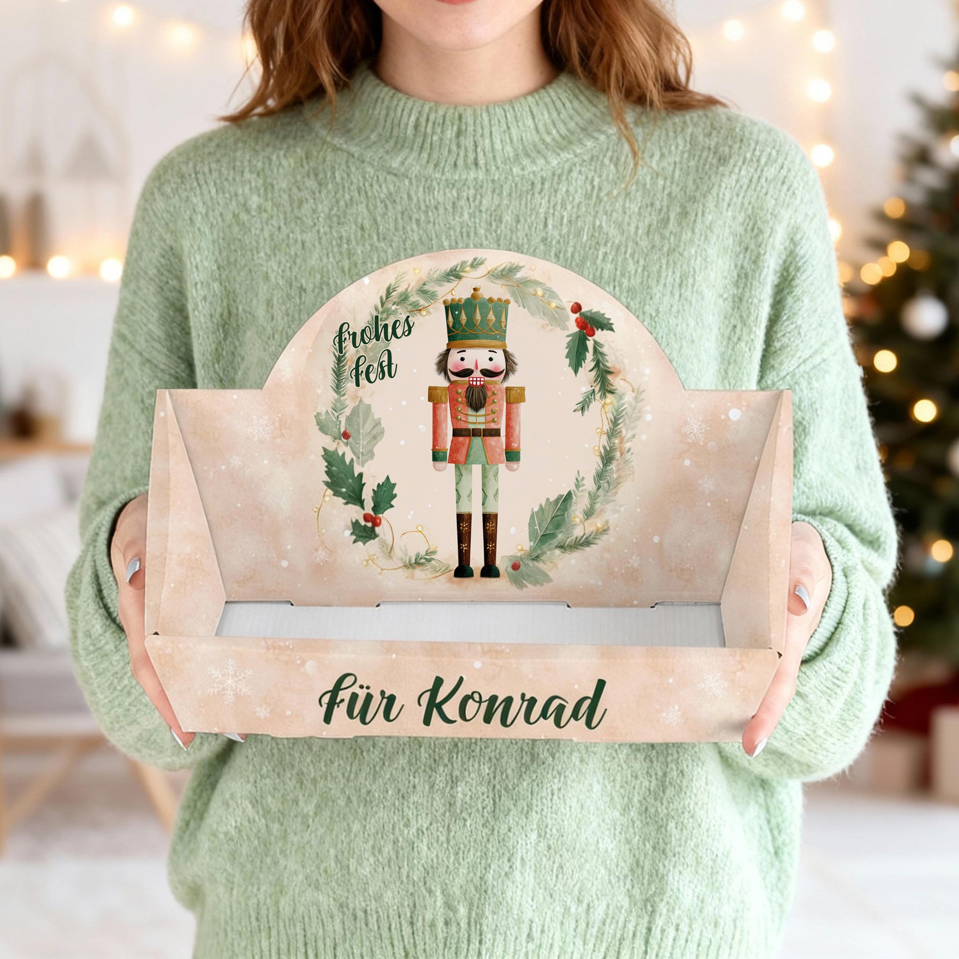 Person hält weihnachtlichen Geschenkkorb mit Nussknacker und Wunschtext