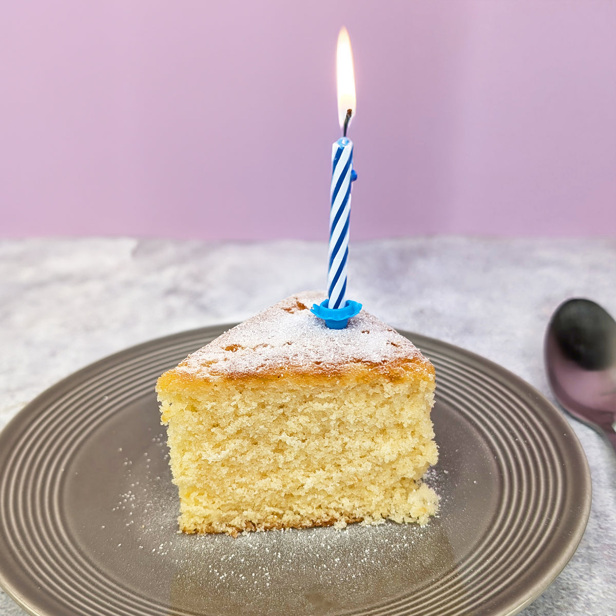 Aufgeschnittenes Stück Kuchen mit Kerze auf Teller angerichtet