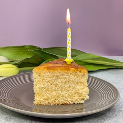 Aufgeschnittenes Stück Kuchen mit Kerze auf Teller angerichtet