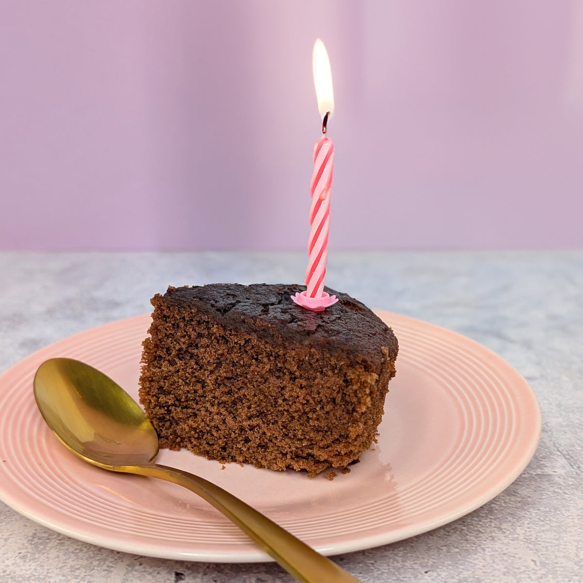 Aufgeschnittenes Stück Kuchen mit Kerze auf Teller angerichtet