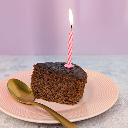 Aufgeschnittenes Stück Kuchen mit Kerze auf Teller angerichtet