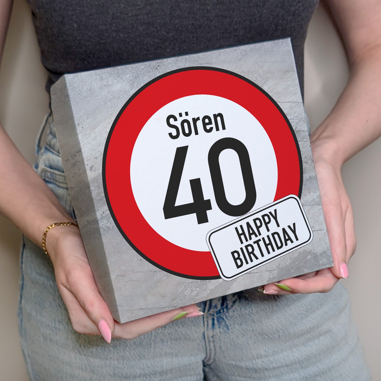 Person hält Geburtstagsbox mit Verkehrszeichen „40“ und Name Sören in beiden Händen vor dem Körper