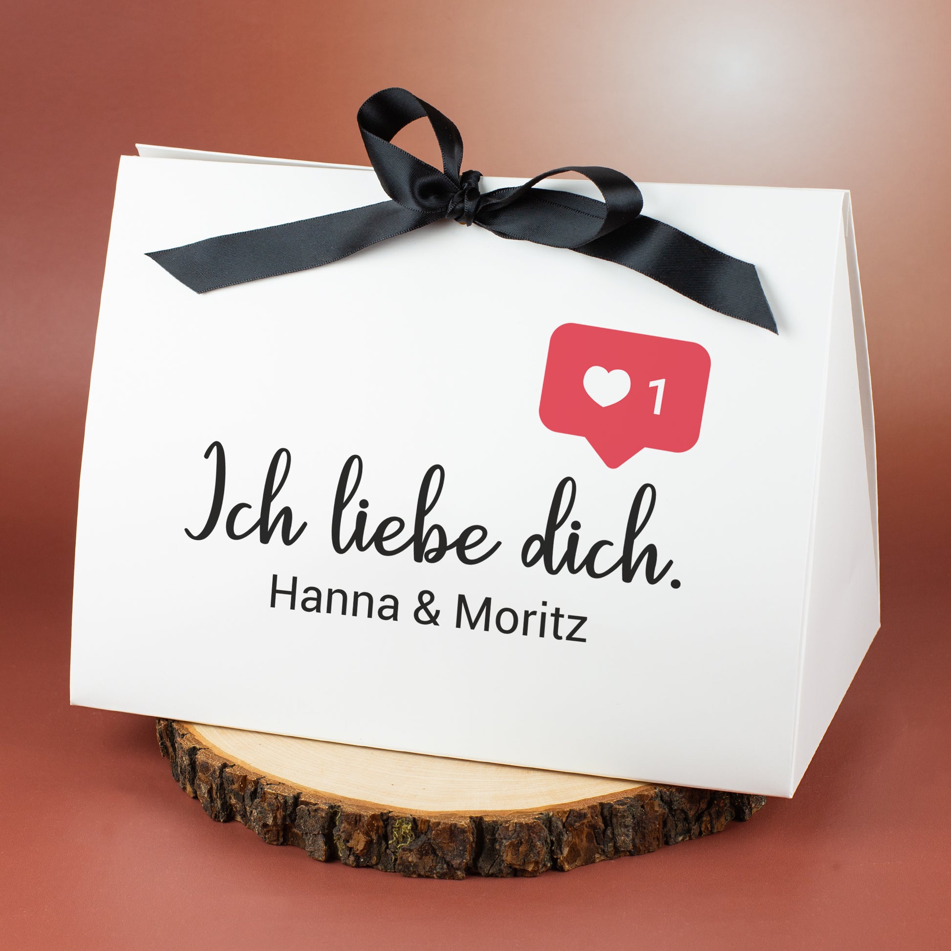 Große Geschenkverpackung mit schwarzer Schleife und Schriftzug „Ich liebe dich“ sowie Namen „Hanna & Moritz“ als personalisierte Widmung