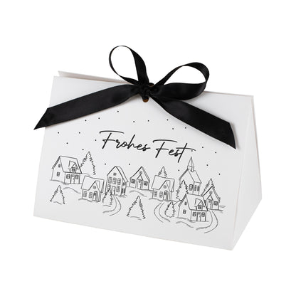 Freigestellte Weihnachtsgeschenktasche mit Winterdorf-Motiv und Aufschrift „Frohes Fest“ vor weißem Hintergrund.