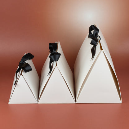 Seitenansicht der Geschenkverpackungen in drei Größen – weiße Faltverpackung mit schwarzer Schleife