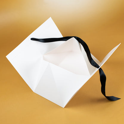 Offene Geschenkverpackung aus weißem Karton mit Satinband – Innenansicht zum Befüllen