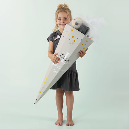 Mädchen mit hellgrauer Schultüte „Lisa“ und goldenen Punkten