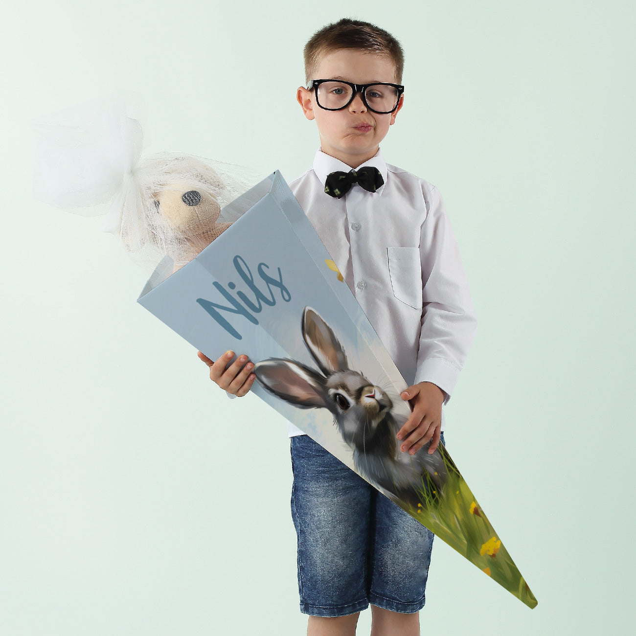 Kind mit personalisierter Schultüte mit Hasenmotiv und dem Namen „Nils“