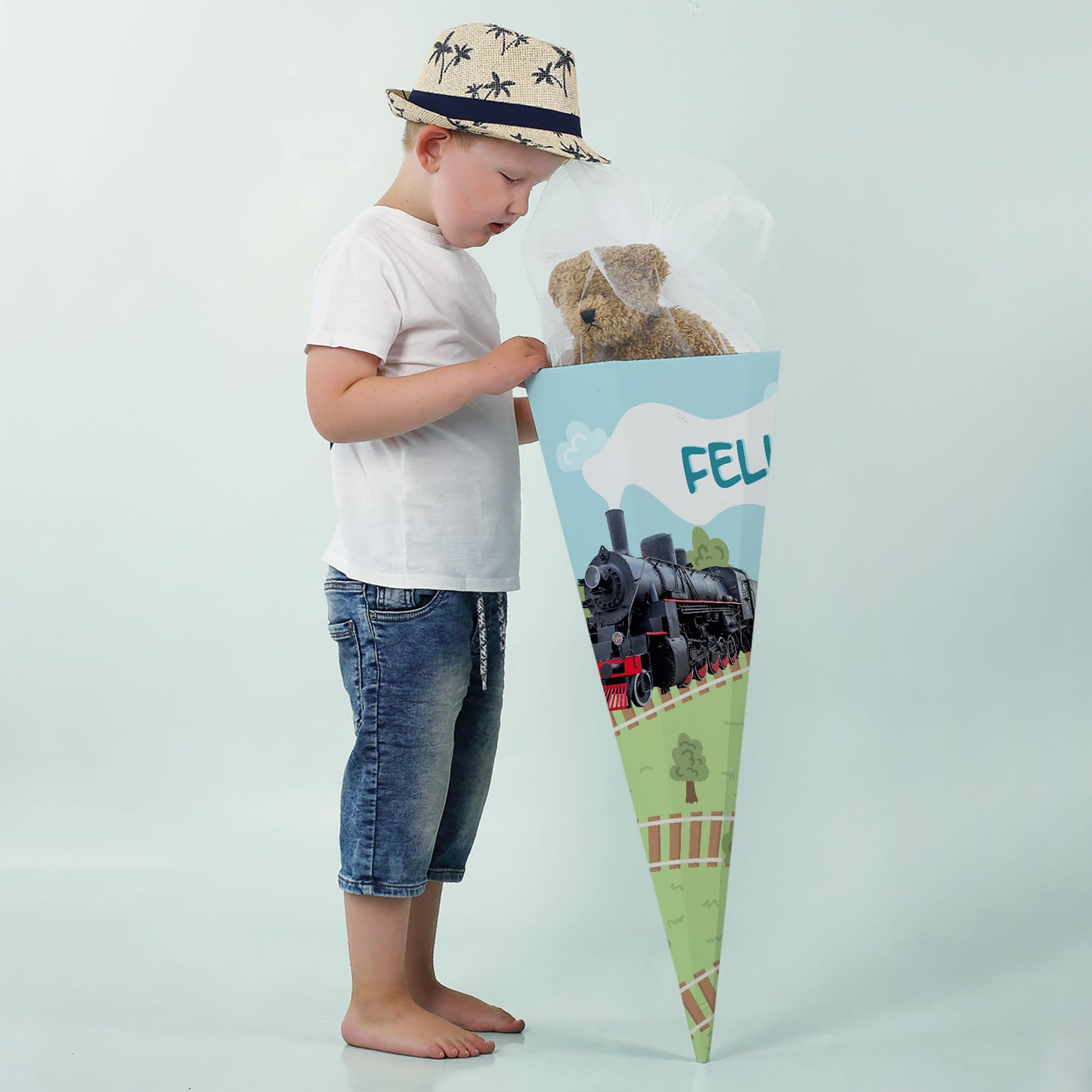 Junge mit Schultüte und Dampflok-Motiv, Teddybär im Inneren