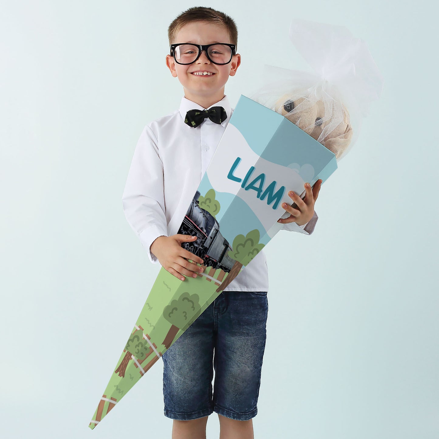 Junge mit Brille und Schleife hält personalisierte Dampflok-Schultüte