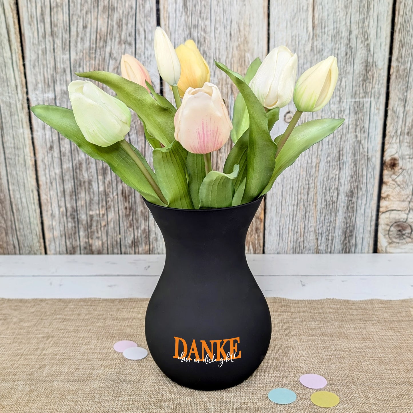 Schwarze Vase mit Tulpen als stilvolle Dekoration auf Tisch platziert