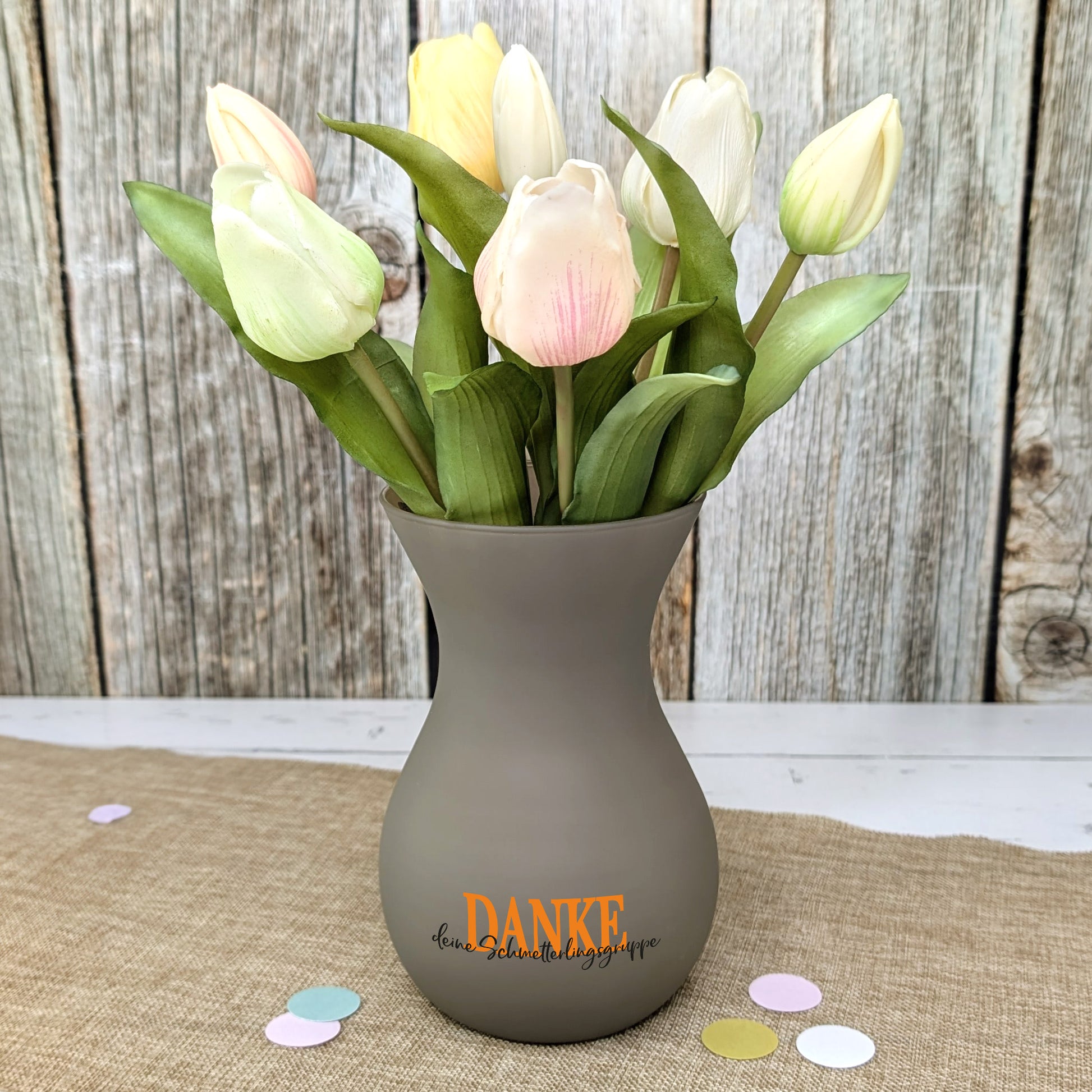 Braune Vase mit Tulpen als stilvolle Dekoration auf Tisch platziert