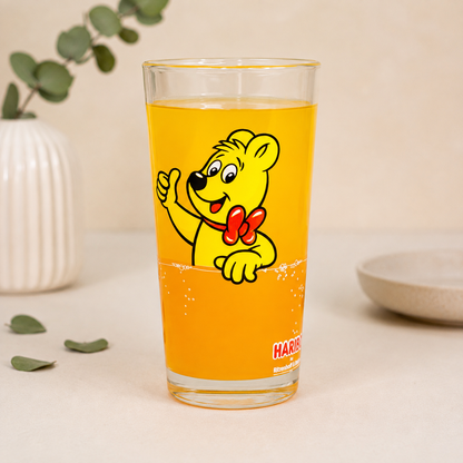 HARIBO Trinkglas ohne Personalisierung mit Goldbär Motiv, orangem Getränk und dezenter Deko auf hellem Hintergrund