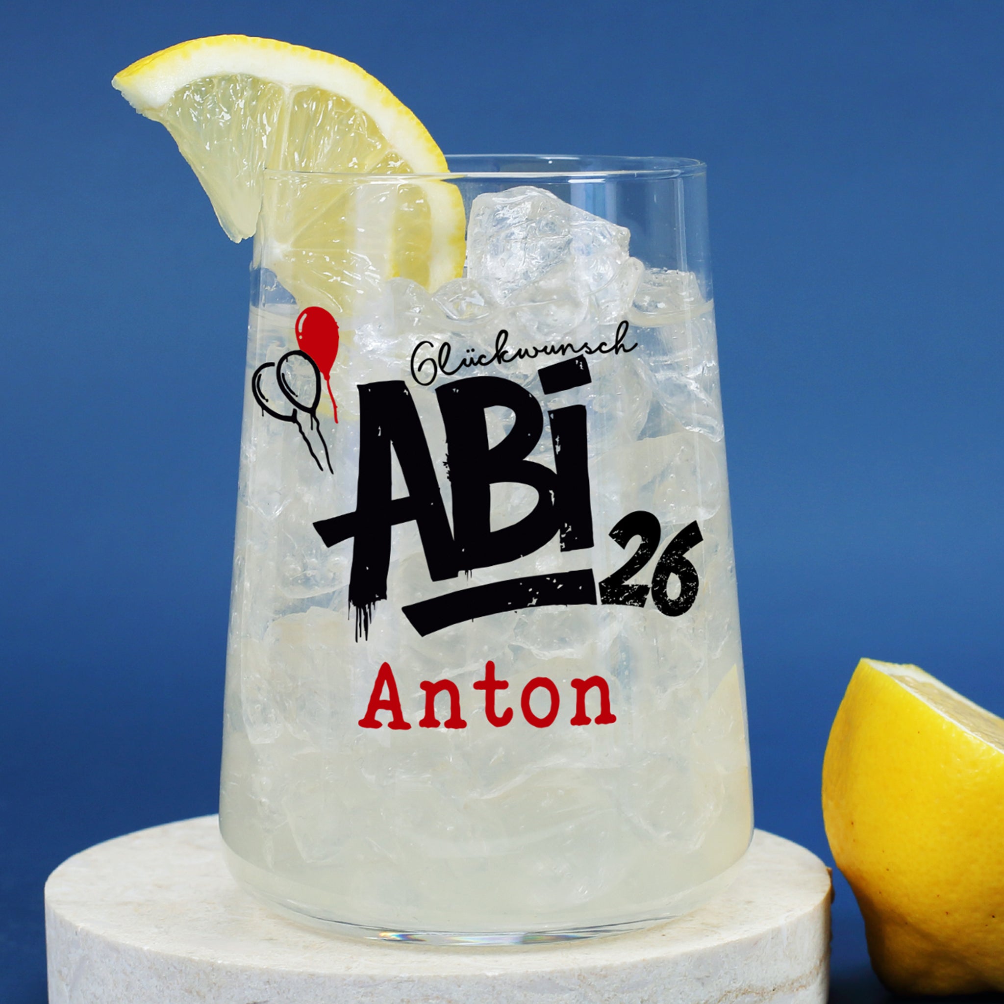 Abi 26 Trinkglas mit Name personalisiert, Eiswürfeln und Zitrone vor blauem Hintergrund