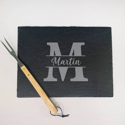 Schieferplatte mit Gravur „Martin“ und Initiale „M“, daneben Grillgabel mit Holzgriff – fotografiert von oben