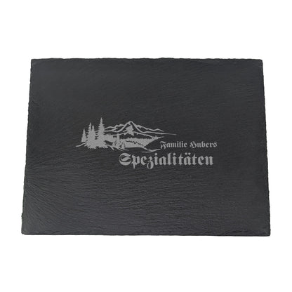 Schieferplatte mit Gravur „Familie Hubers Spezialitäten“ und rustikalem Naturmotiv auf weißem Hintergrund