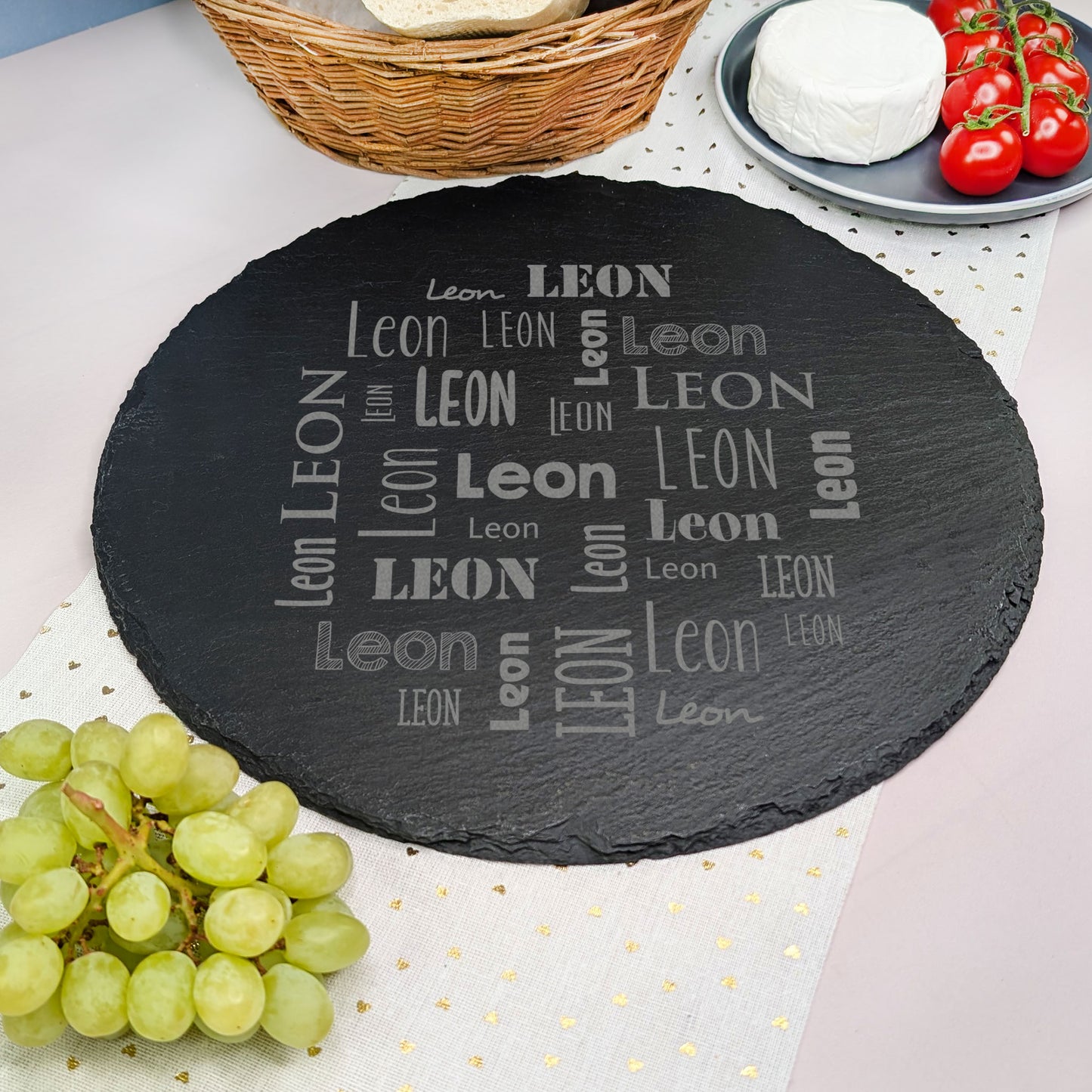 Schieferplatte mit Gravur „Leon“, serviert mit Weintrauben und Tomaten, Korb im Hintergrund