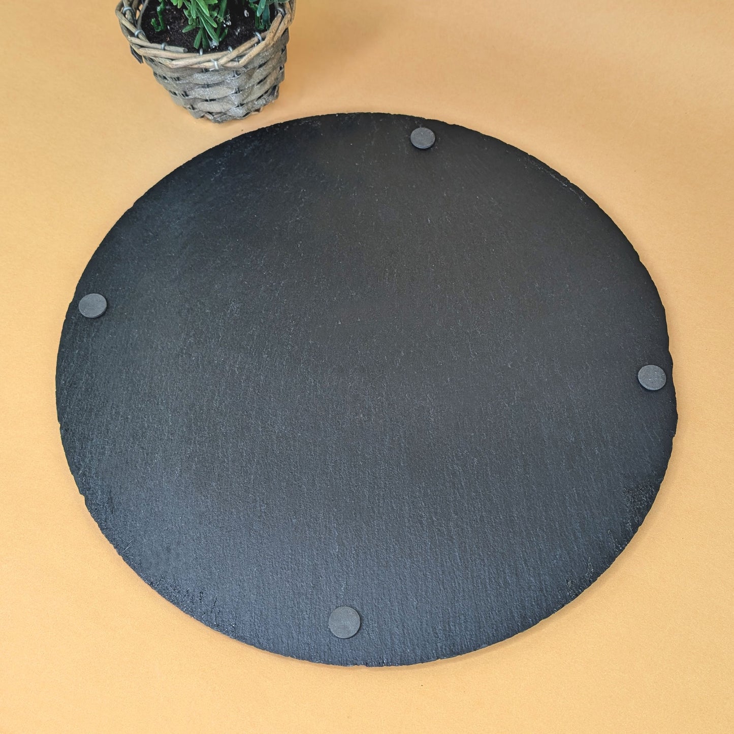 Unterseite der runden Schieferplatte mit vier rutschfesten Füßen, auf gelber Fläche