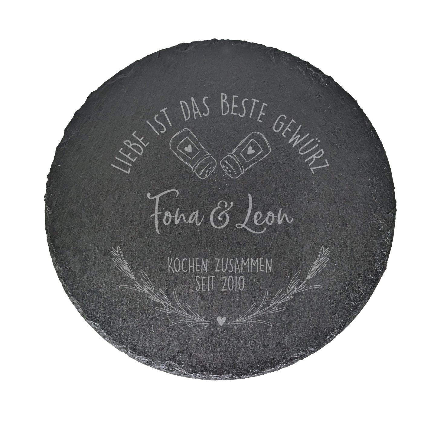 Produktansicht der runden Schieferplatte mit Gravur „Fiona & Leon – Kochen zusammen seit 2010“ auf weißem Hintergrund