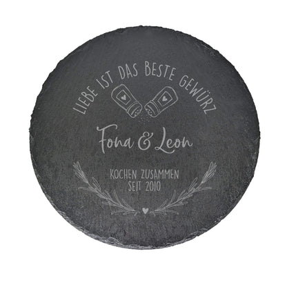 Produktansicht der runden Schieferplatte mit Gravur „Fiona & Leon – Kochen zusammen seit 2010“ auf weißem Hintergrund