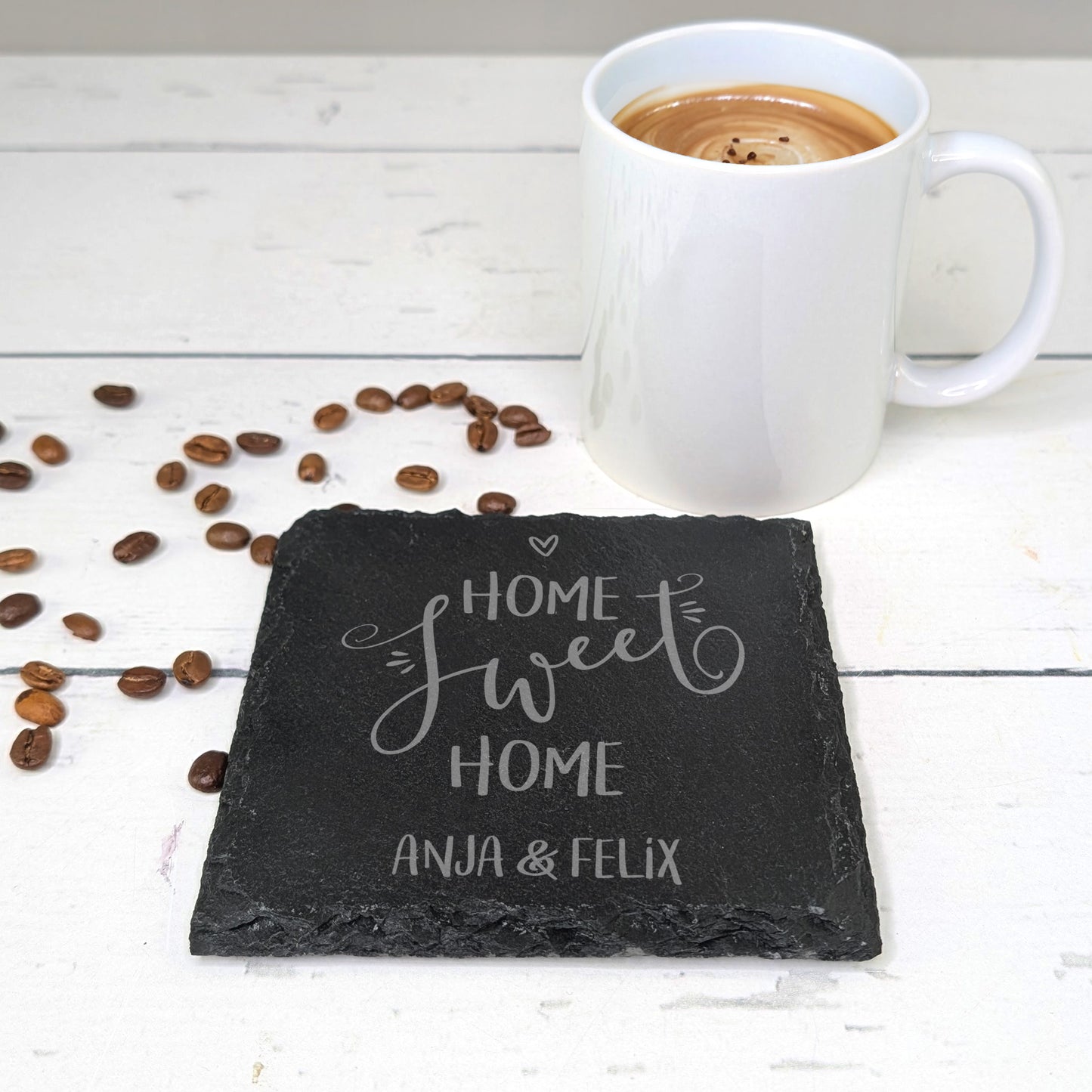 Gravierte Schieferplatte mit „Home sweet Home“ Gravur, daneben Kaffeetasse und Bohnen