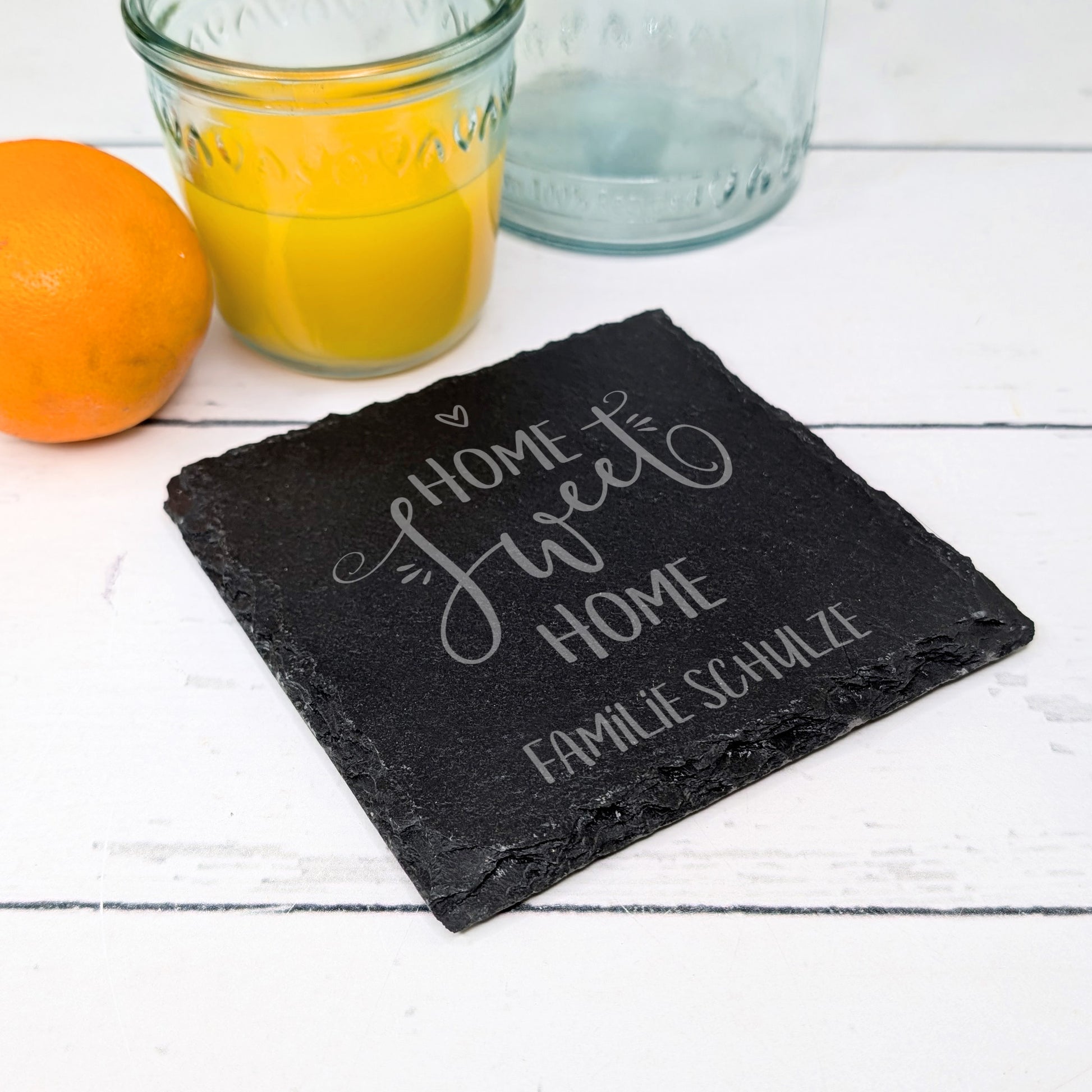 Schiefer-Untersetzer mit Namensgravur, dekoriert mit Orangensaft und Glas