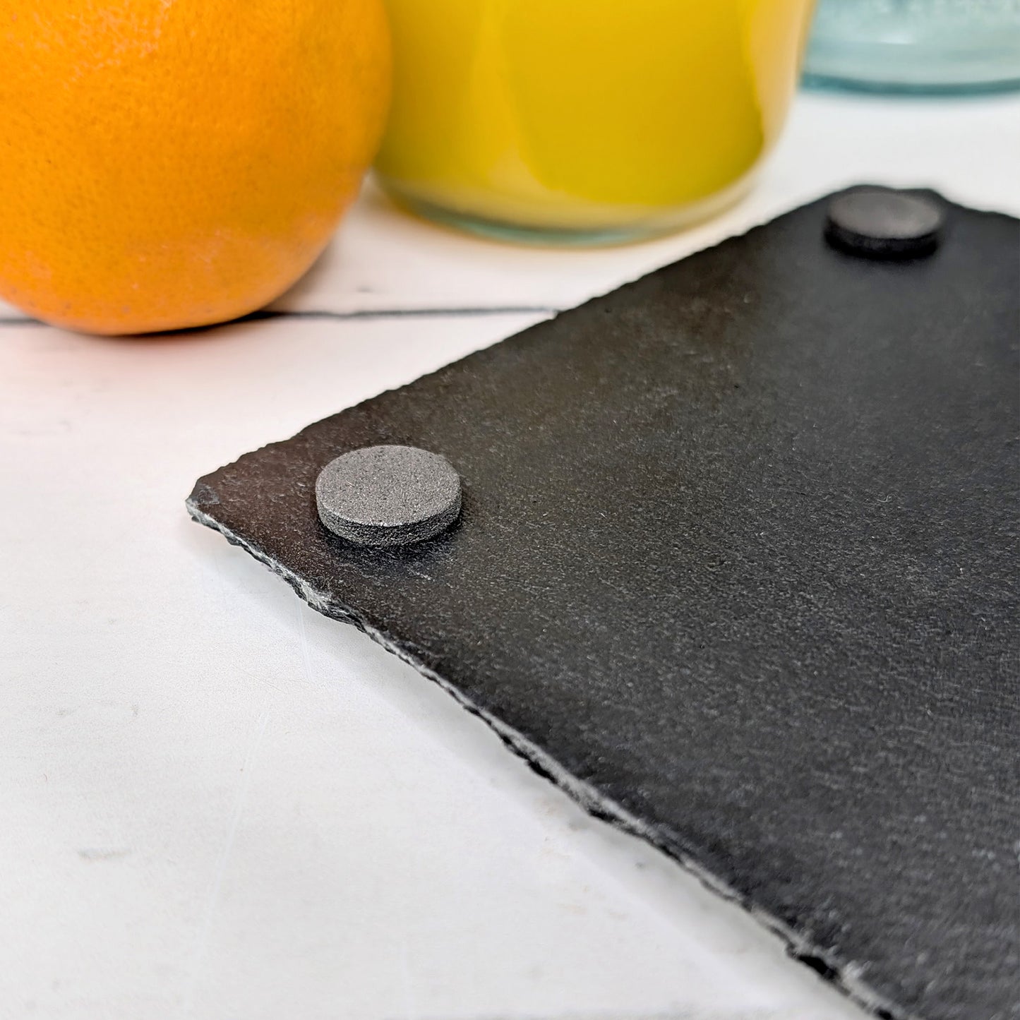 Nahaufnahme des Schieferuntersetzers mit strukturierter Kante und Anti-Rutsch-Füßen auf der Rückseite