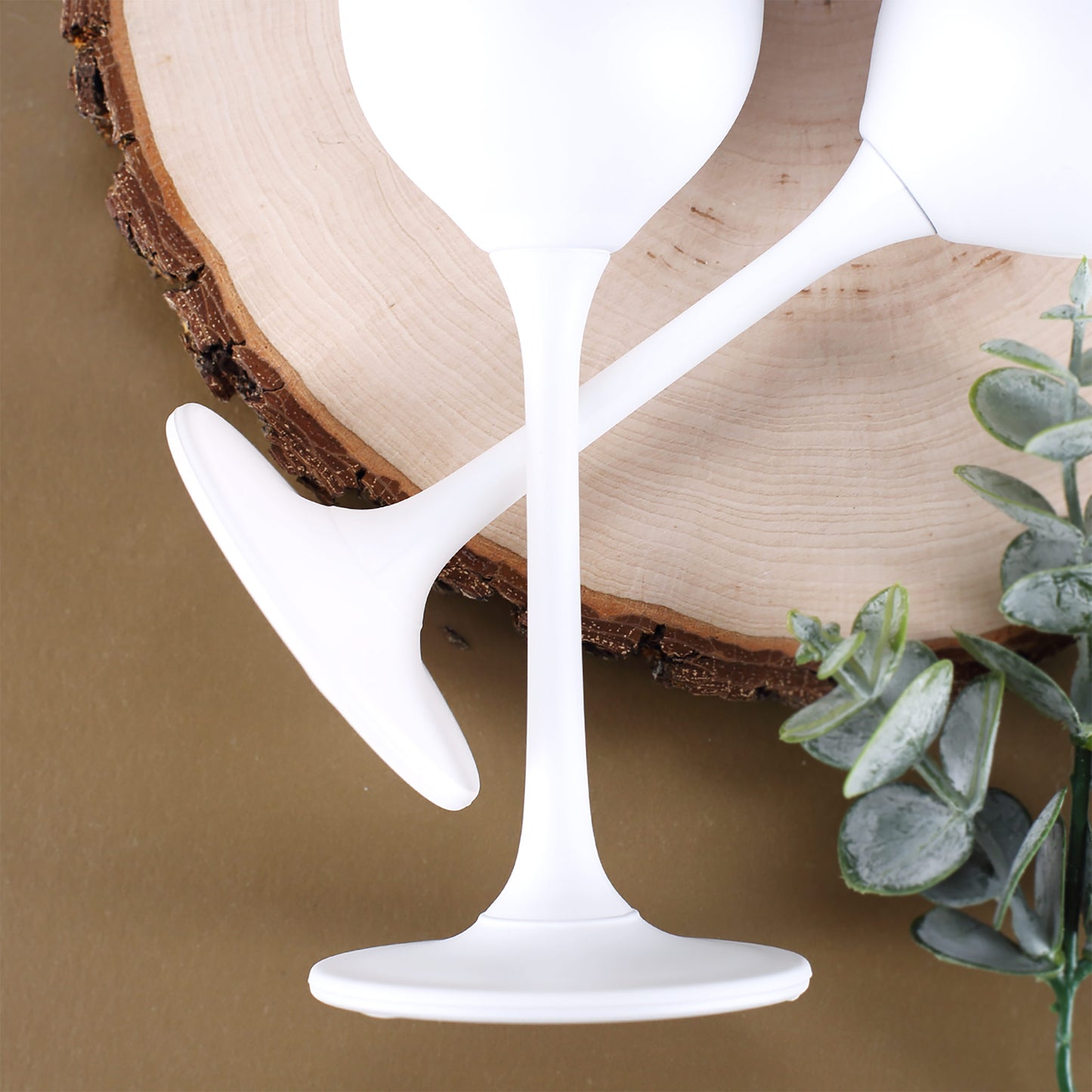 Nahaufnahme der weißen Glasfüße zweier Gläser auf Holzunterlage