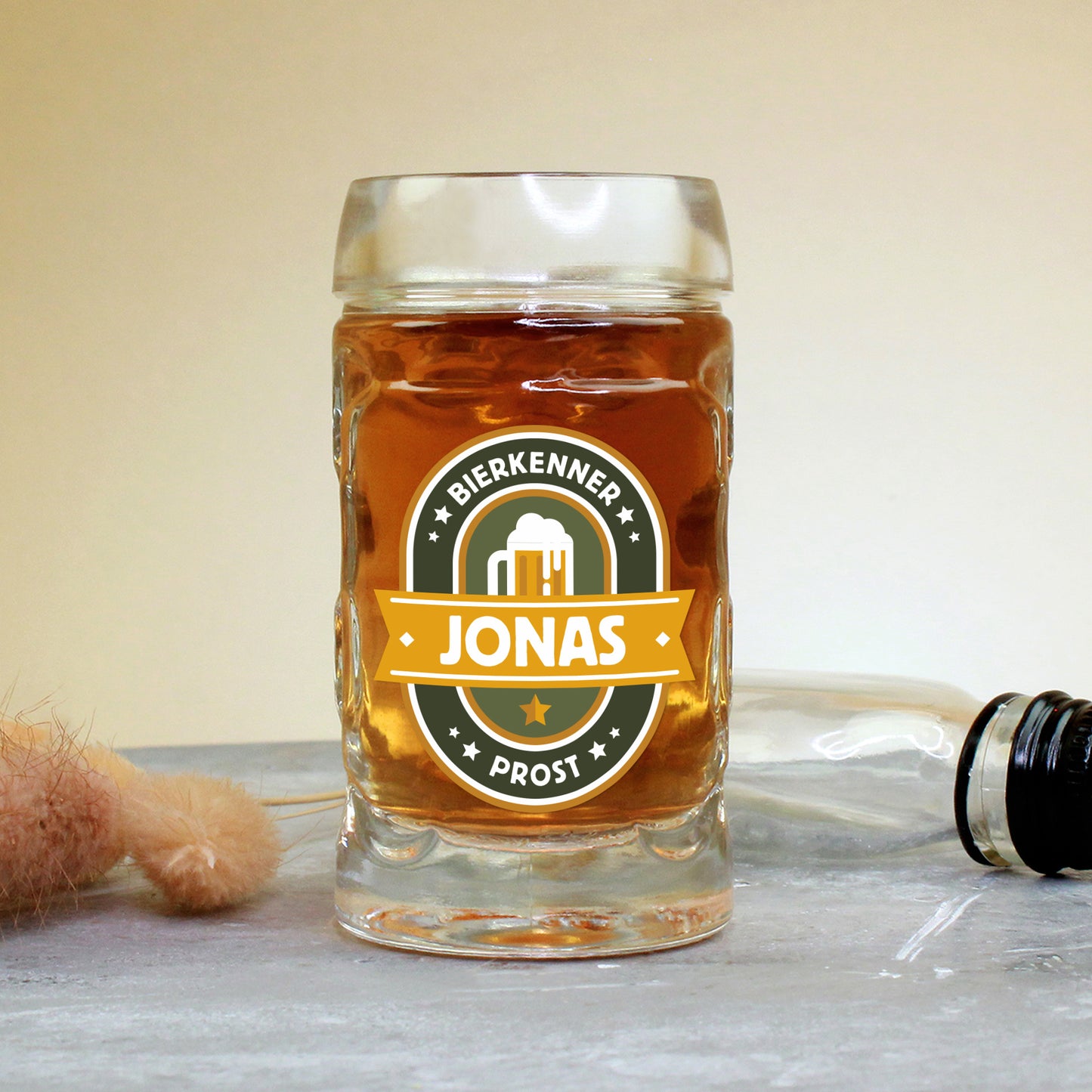 Mini-Bierkrug mit Henkel und 4 cl Inhalt, rechts im Bild eine kleine Likörflasche, vorn der Namensaufdruck „Jonas“ im Bierkenner-Design – eignet sich perfekt als Gag-Geschenk oder Ergänzung zu Männerpräsenten