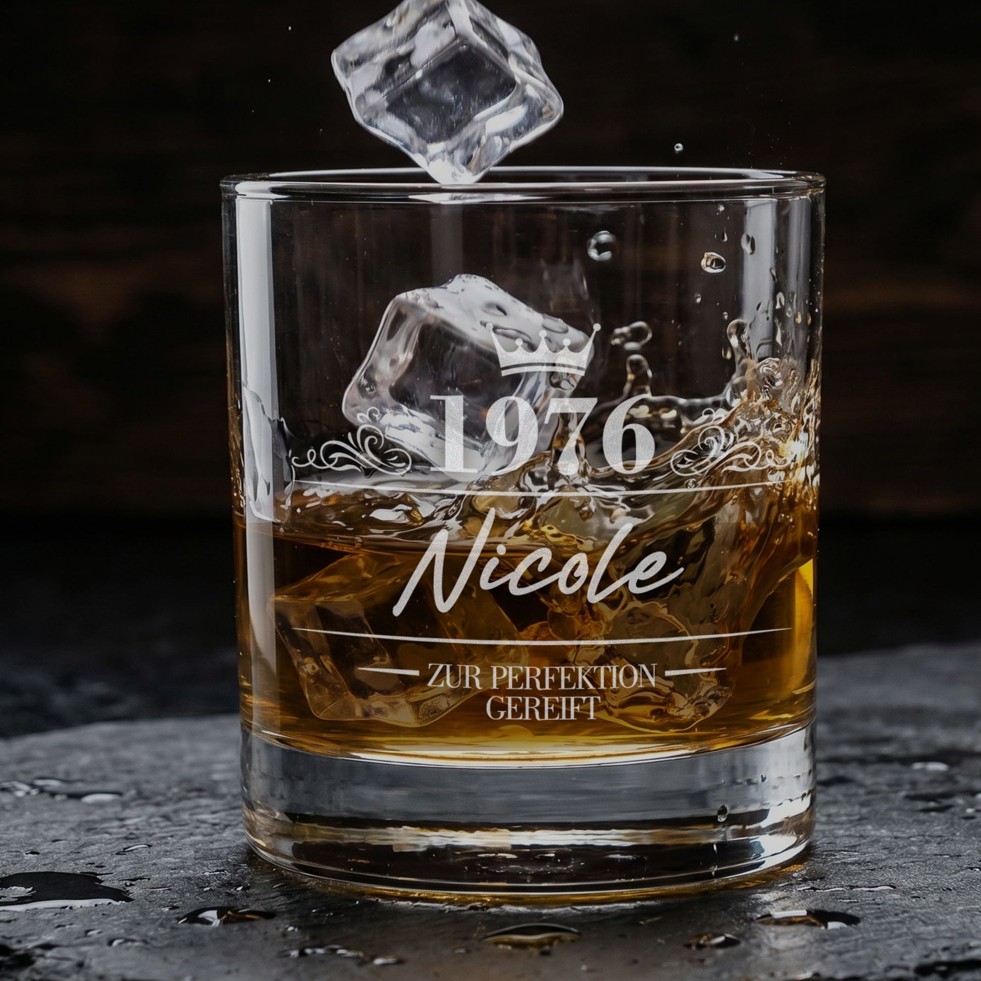 Personalisiertes Whiskyglas mit Gravur von 1976, Name Nicole und Krone, mit Eiswürfeln und Whiskysplash