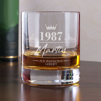 Personalisiertes Whiskyglas mit Gravur von 1987, Name Martin und Krone, gefüllt mit Whisky auf Tisch