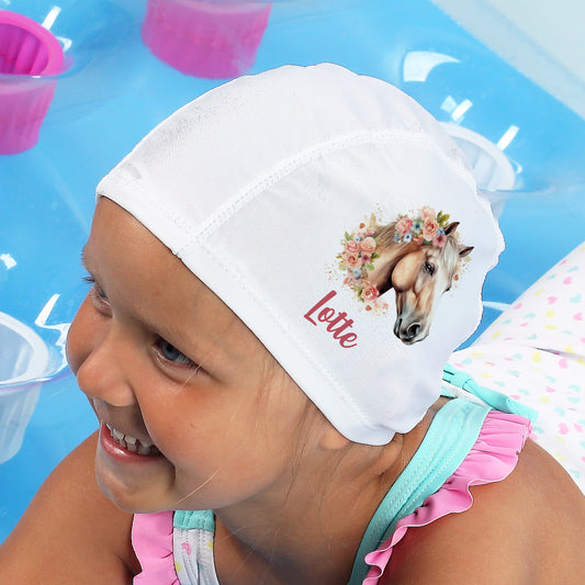 Mädchen trägt Badekappe mit Pferdemotiv und Name „Lotte“ am Pool